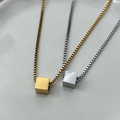 Two necklaces with square pendants on a light gray background