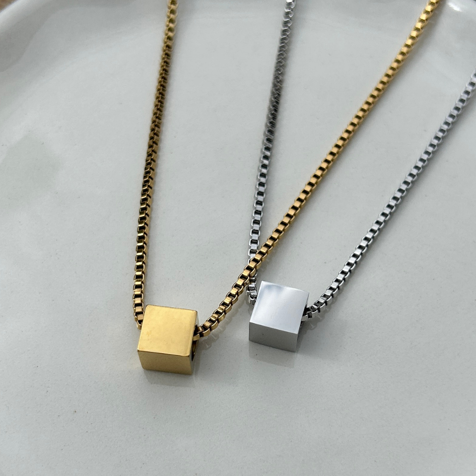 Two necklaces with square pendants on a light gray background