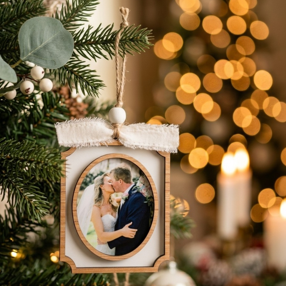Decorative photo ornament with a couple's picture on a Christmas tree with lights in the background.
