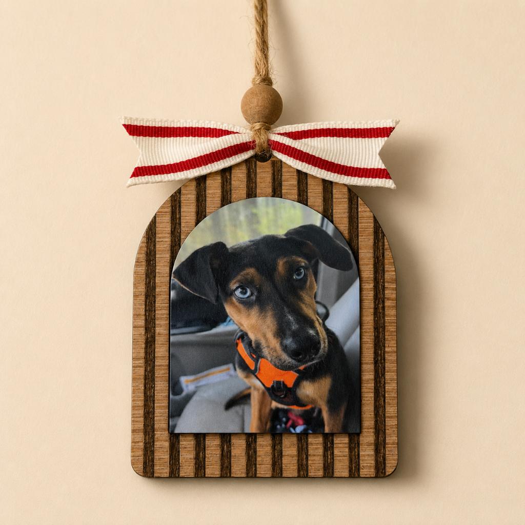 Wooden ornament with a photo of a dog and a red and white ribbon on a beige background