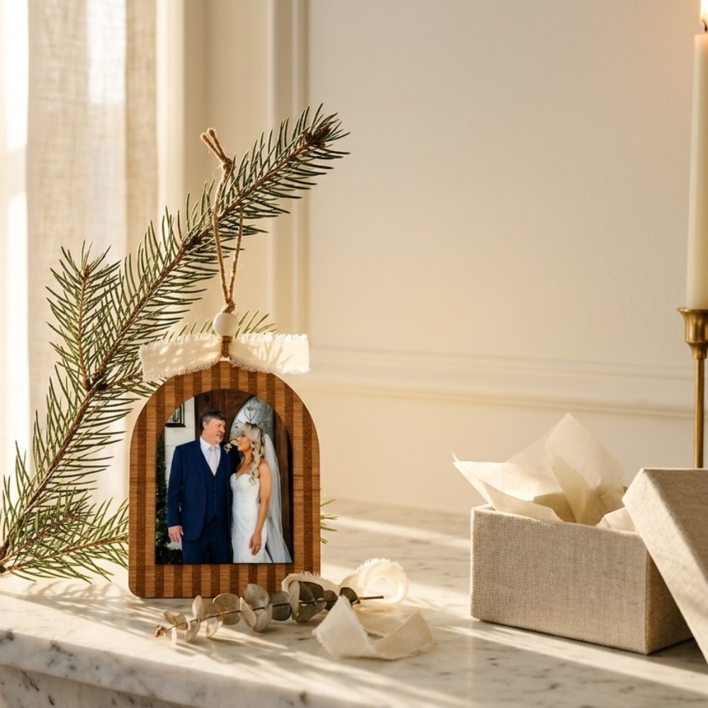 Decorative photo ornament with a father and daughter's picture, surrounded by a Christmas tree branch and gift box on a marble surface.