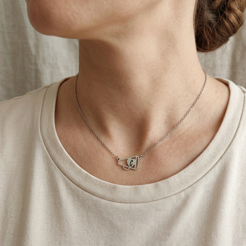 Necklace with a heart-shaped pendant worn by a person in a beige shirt.