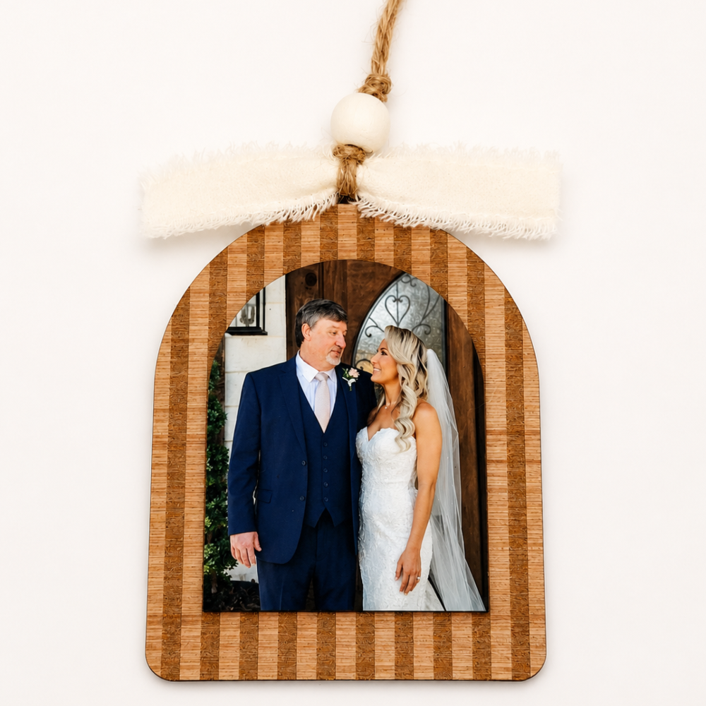 Wooden photo frame with a wedding father and daughter inside, hanging against a white background.