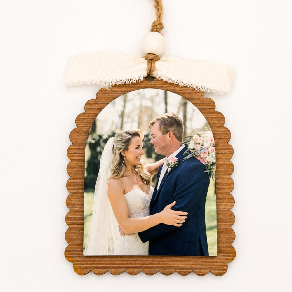 Wooden photo frame with a wedding couple inside, hanging against a white background.