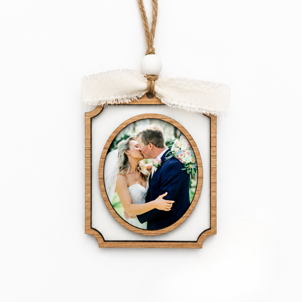 Decorative photo ornament with a couple in a wooden frame on a white background