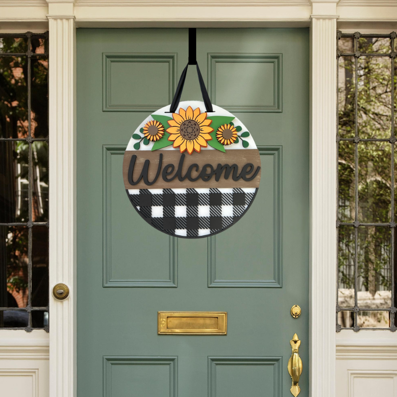 Decorative 'Welcome' sign with sunflowers on a green door.