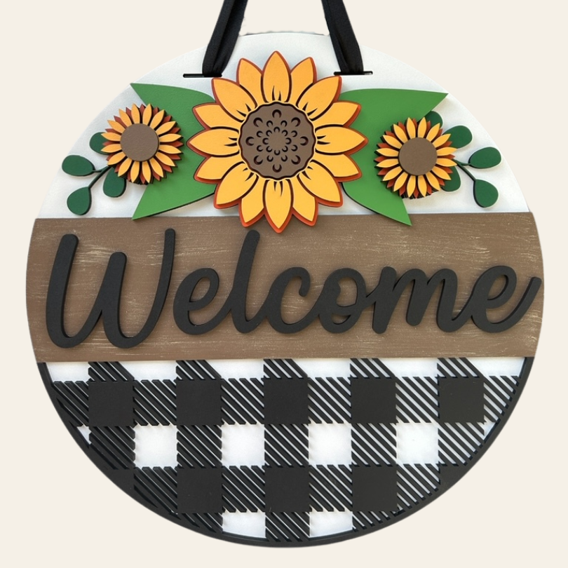 Round wooden sign with sunflowers and 'Welcome' text on a checkered background